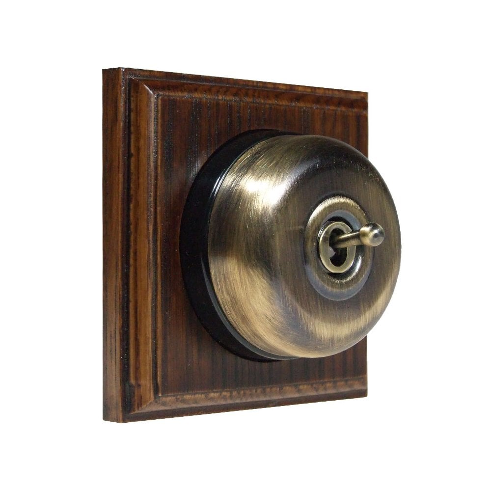 Switch to Wood's Dolly Light Switch Smooth Dome - 1 Gang Square Backplate Antique Brass in Dark Oak