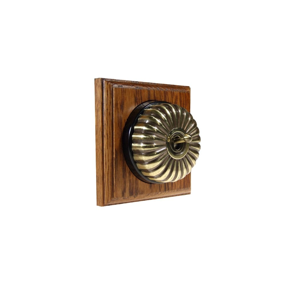 Switch to Wood's Dolly Light Switch Fluted Dome - 1 Gang Square Backplate Antique Brass in Medium Oak 