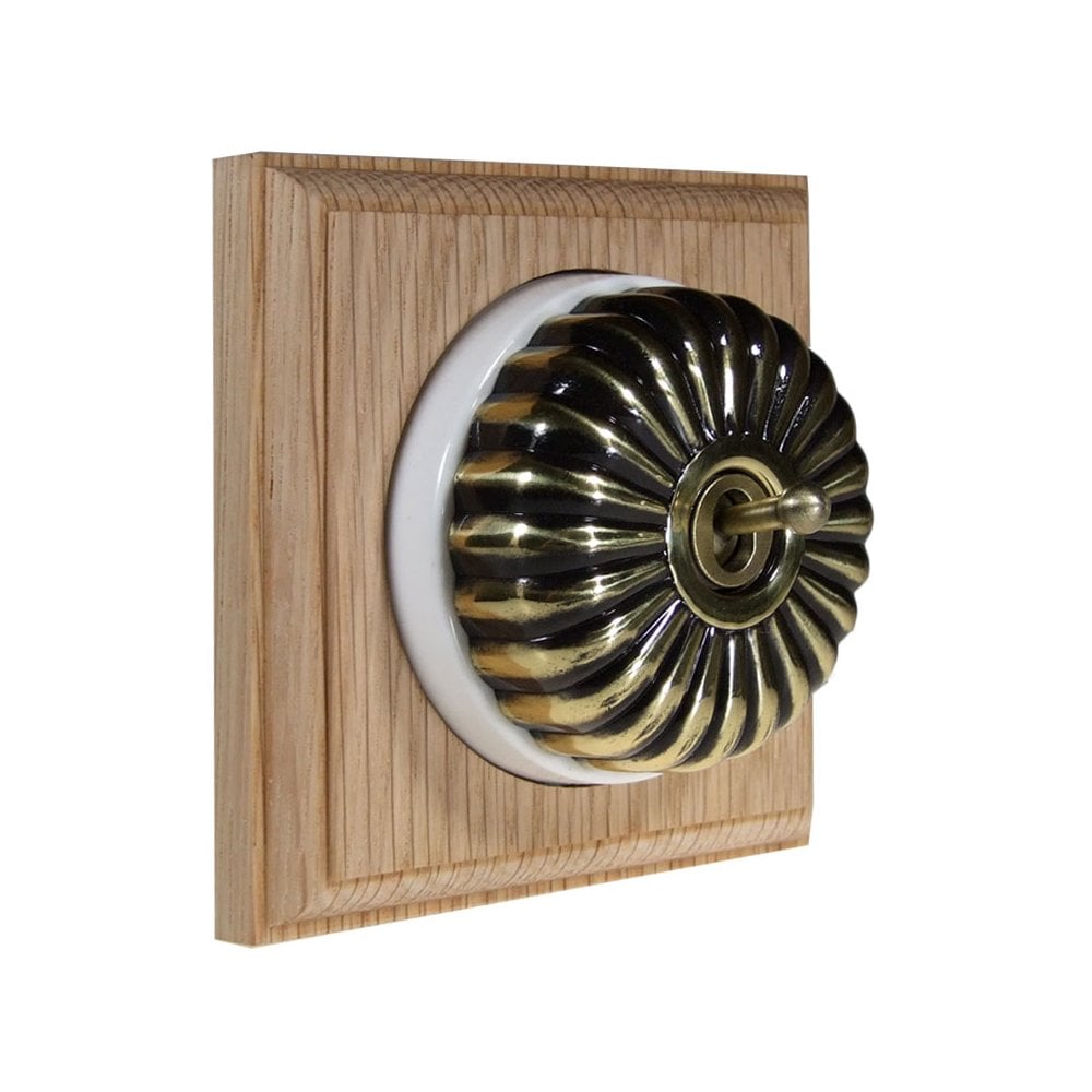 Switch to Wood's Dolly Light Switch Fluted Dome - 1 Gang Square Backplate Antique Brass in Unfinished Oak