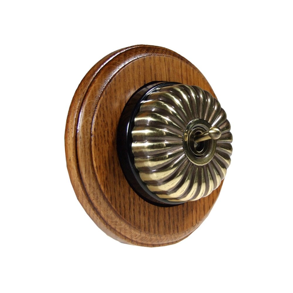 Switch to Wood's Dolly Light Switch Fluted Dome - 1 Gang Round Backplate Antique Brass in Medium Oak 