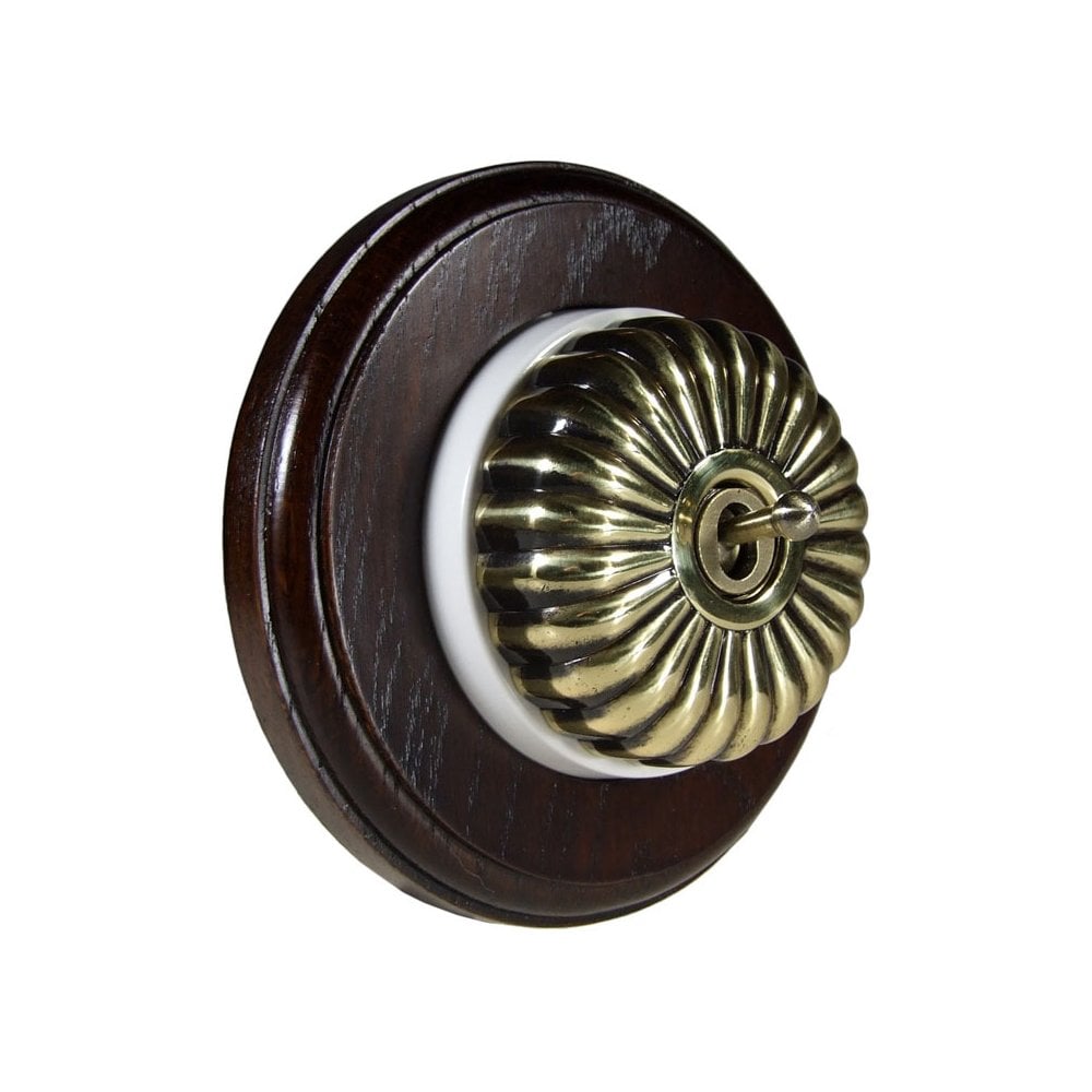 Switch to Wood's Dolly Light Switch Fluted Dome - 1 Gang Round Backplate Antique Brass in Dark Oak